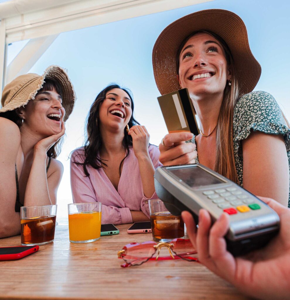 A group of women on vacation handing a card to a waiter with a handheld POS system