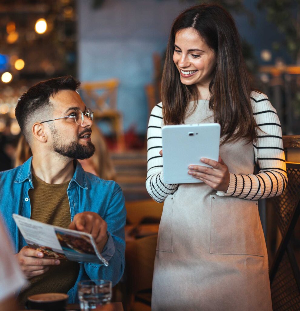 A waitress taking a man's order in a restaurant on a tablet