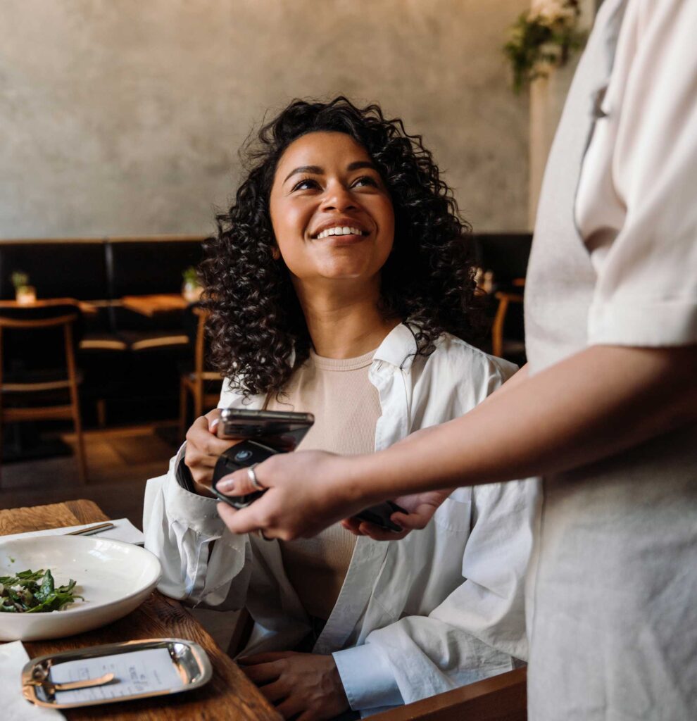 A woman in a restaurant scanning her card on a waitress's phone