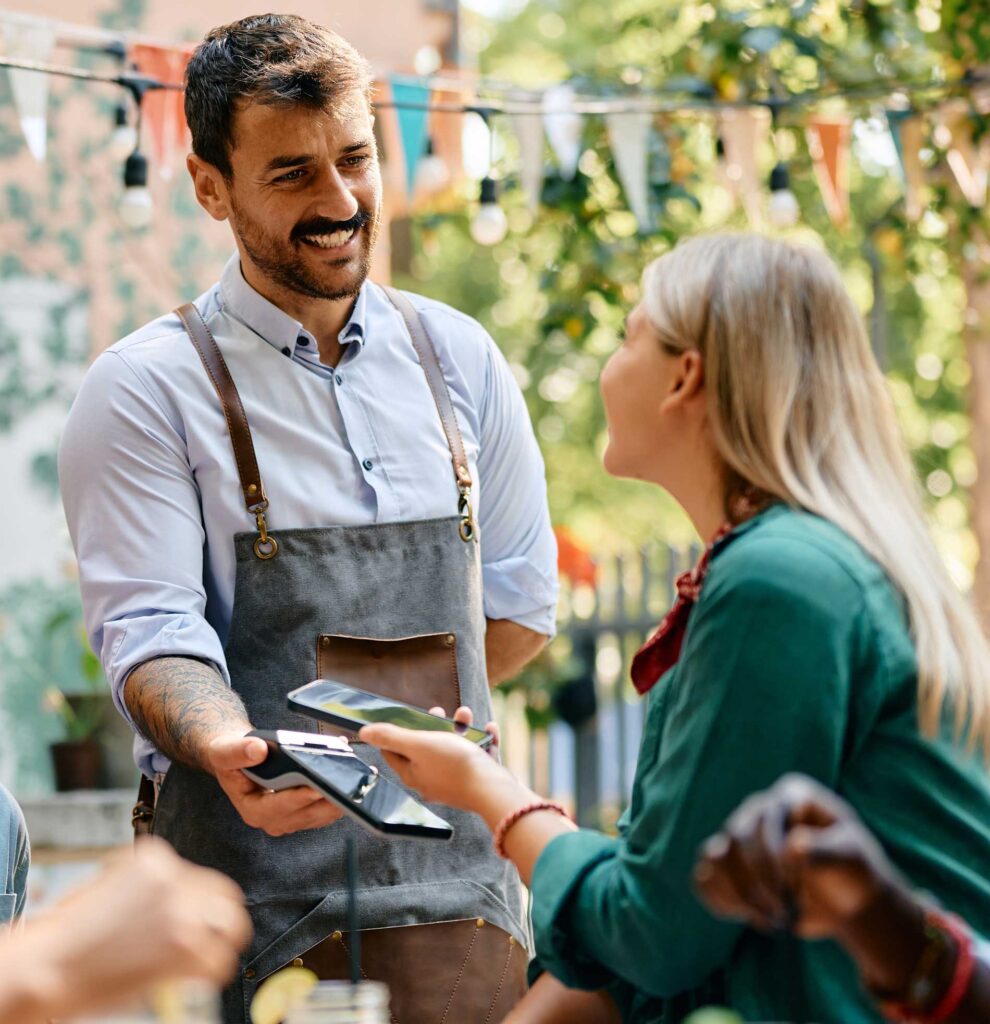 A waiter scanning a customer's phone using a handheld POS device