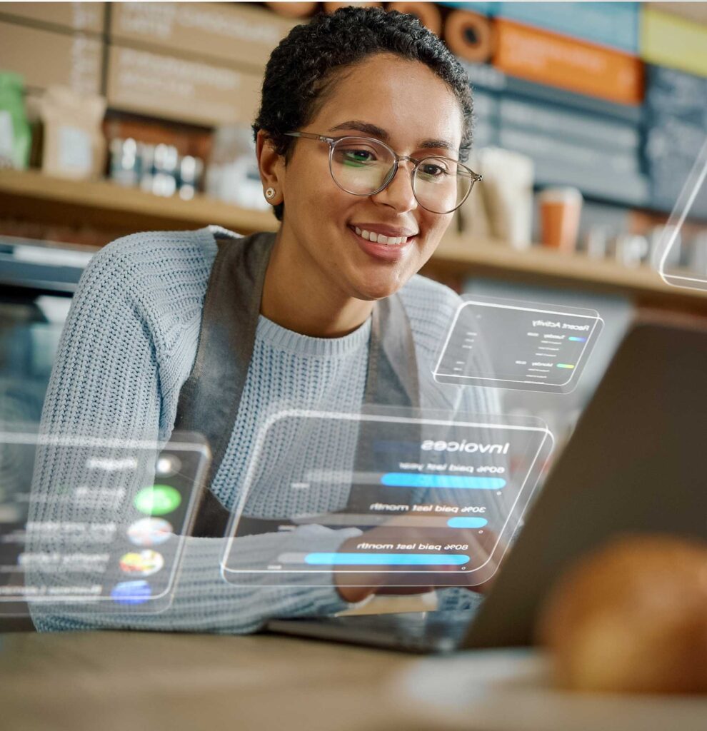 An employee looking at reports on a laptop while working the store counter
