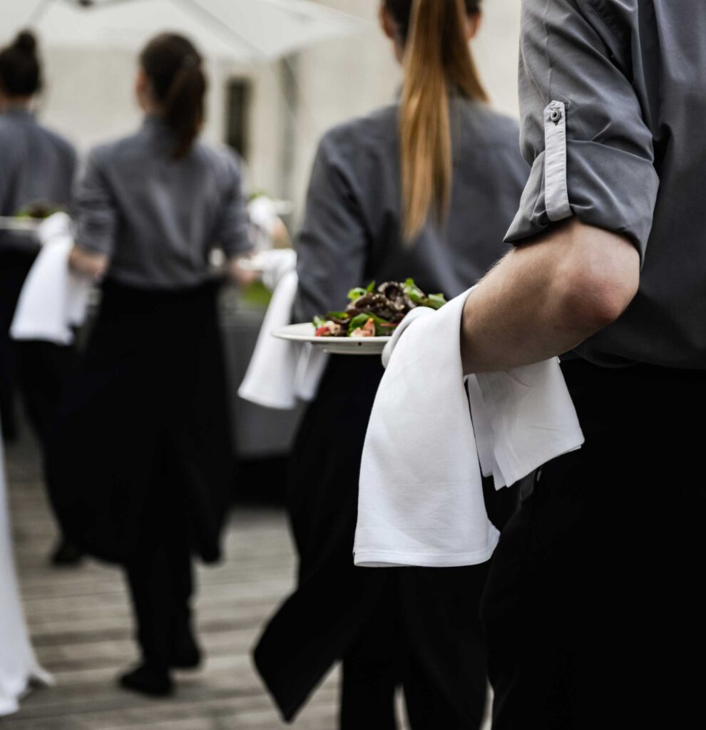 A line of waiters leaving a kitchen with plates of food